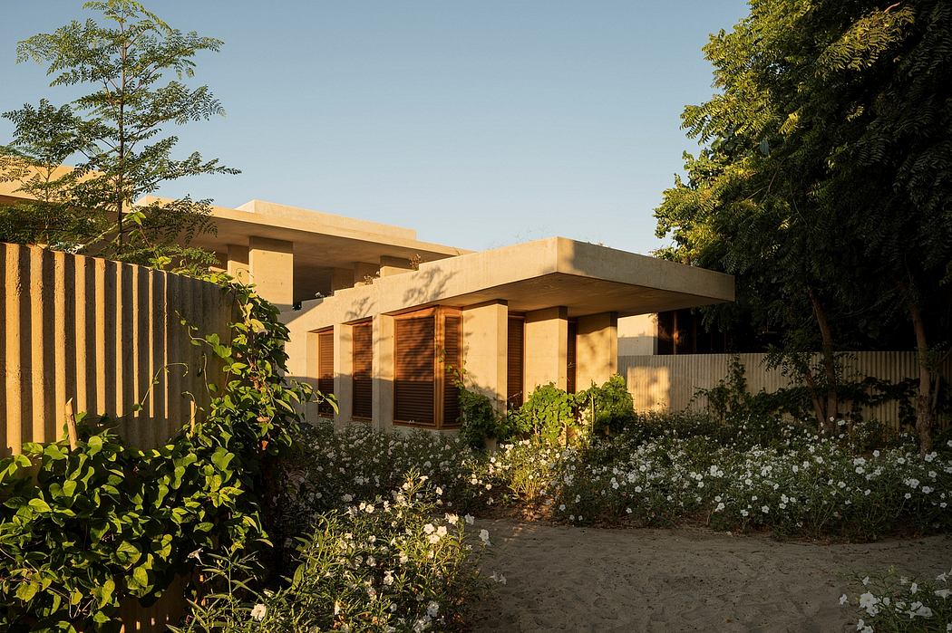 A modern, single-story home with a flat roof, wooden accents, and a lush garden in the foreground.