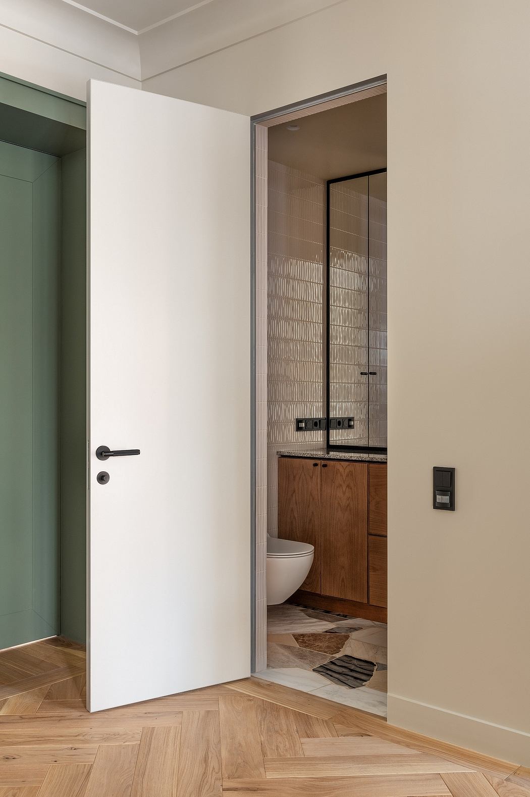 A minimalist interior with a white door, wood paneling, and a recessed bathroom area.