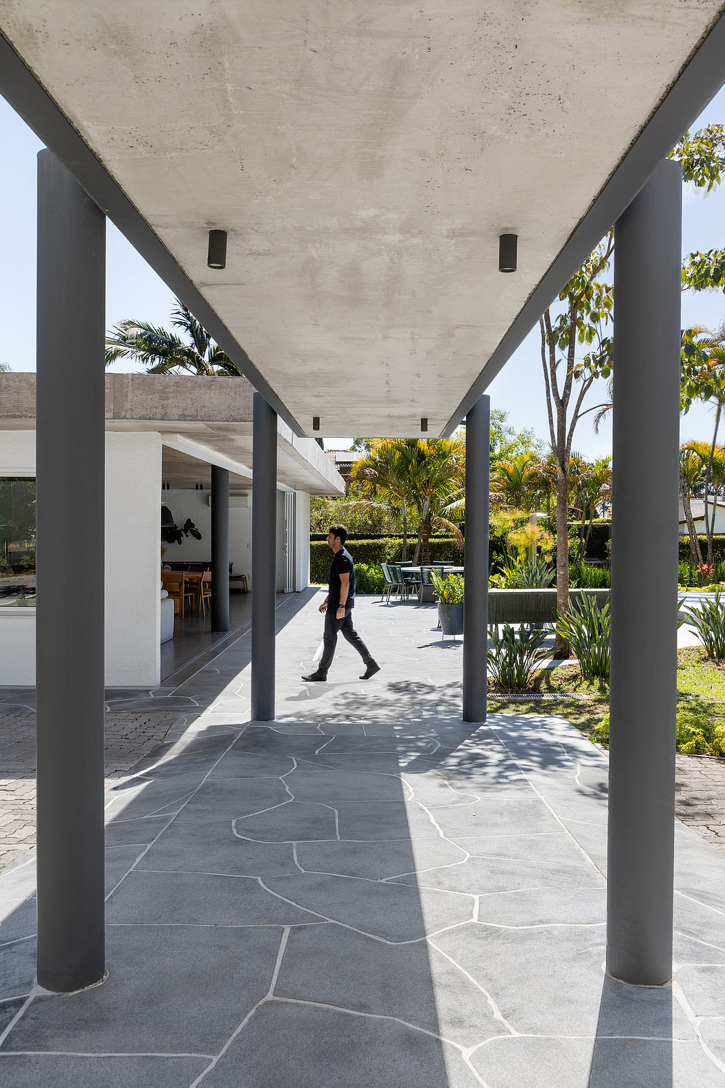 Concrete overhead structure with slender columns, contrasting with lush greenery beyond.