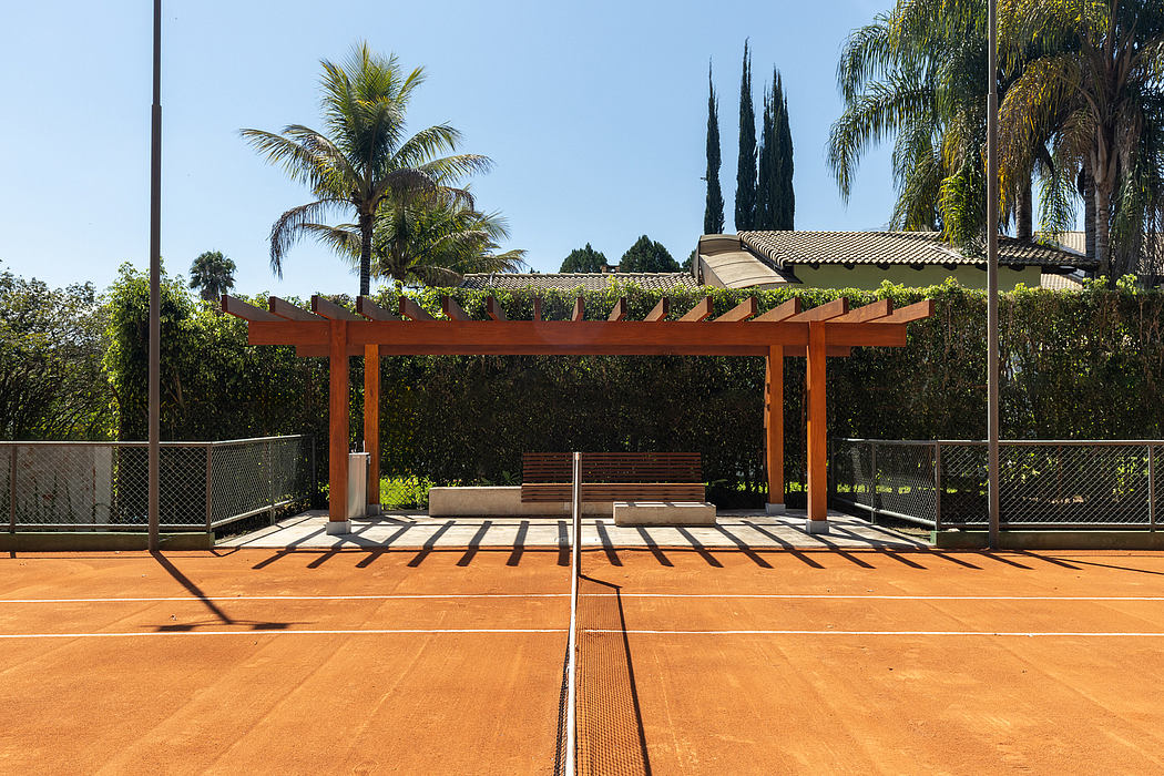 Outdoor tennis court with a wooden pergola and lush tropical vegetation surrounding it.