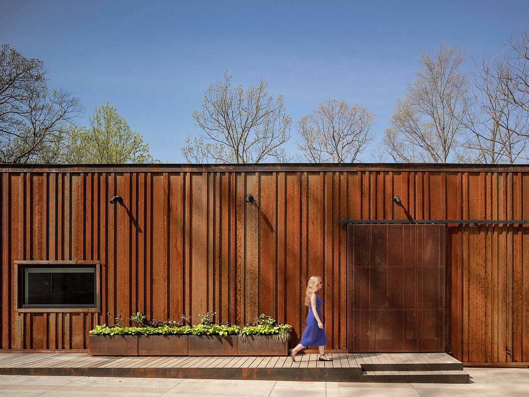 A modern wooden structure with a planted window box and a person walking by.