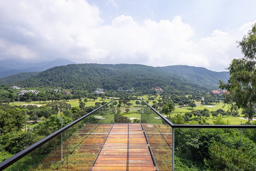 Glass-enclosed walkway with panoramic mountain and landscape view.