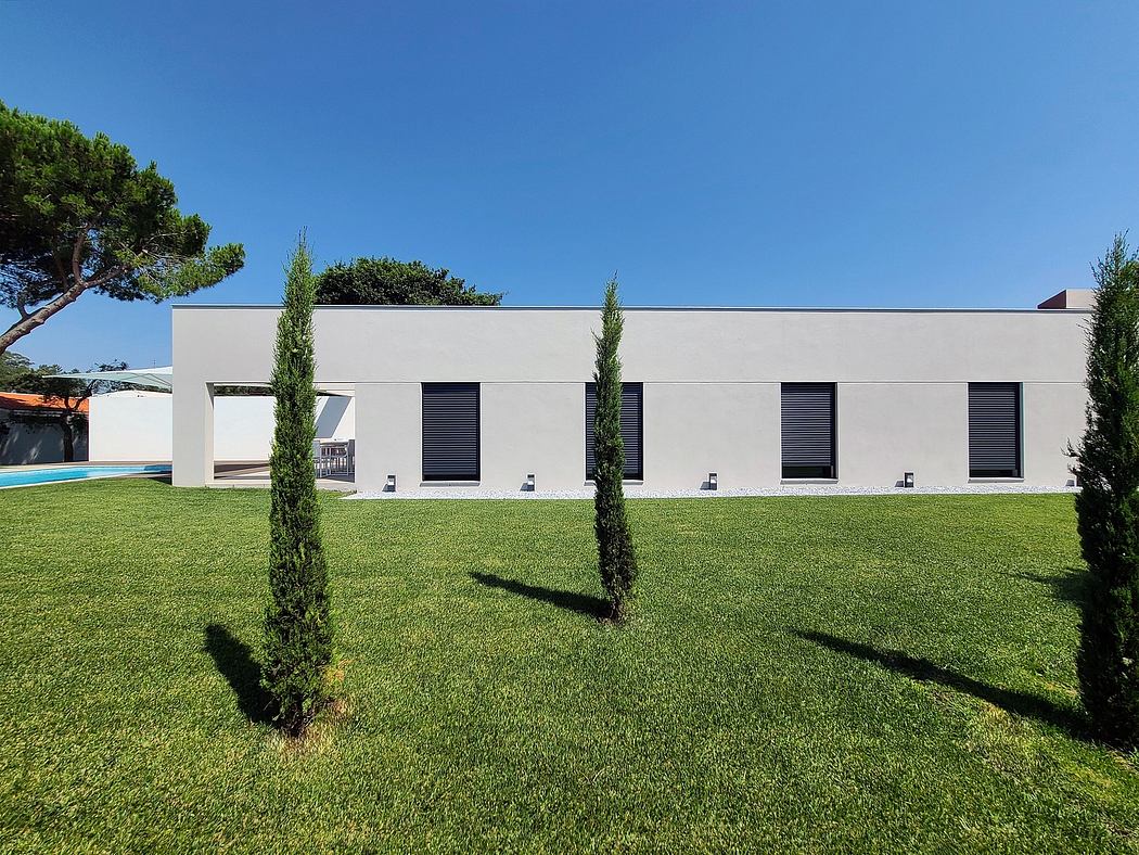 A modern, minimalist building with a clean facade and a lush green lawn in the foreground.