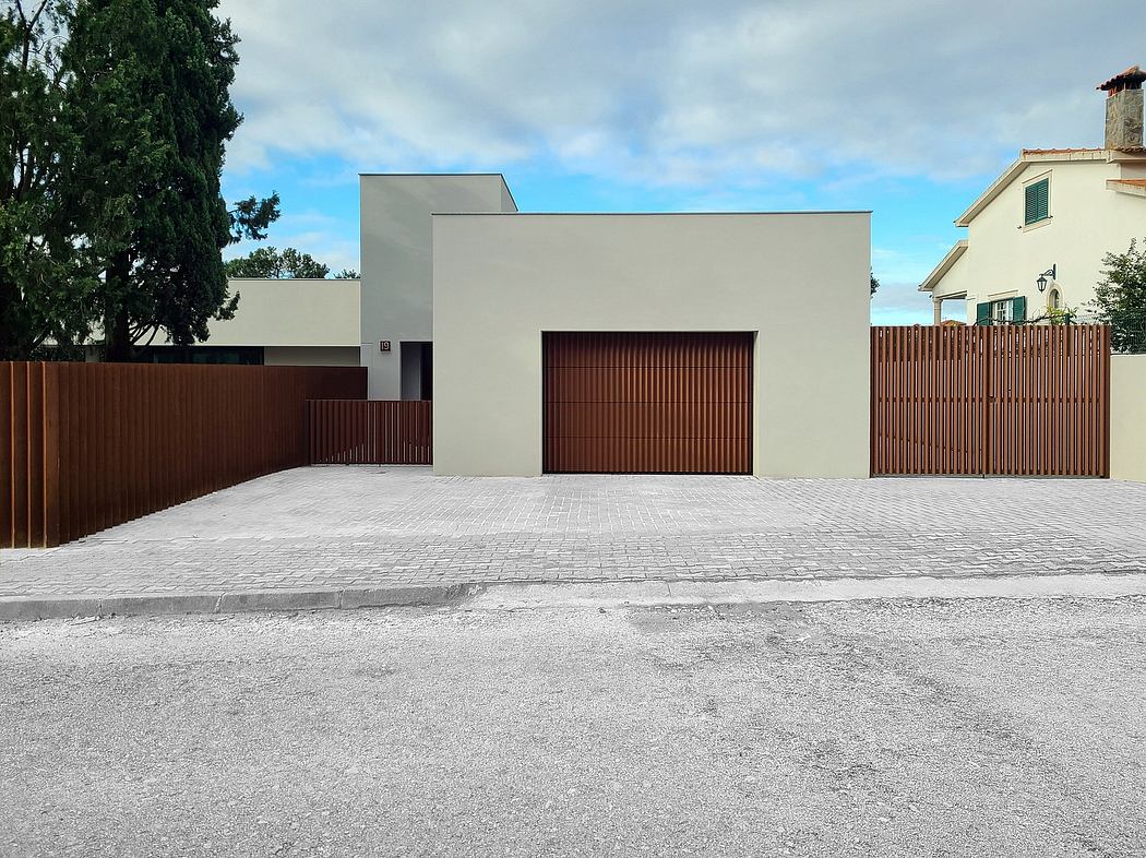 Modern, minimalist building with flat roof, wood-paneled garage doors, and paved courtyard.