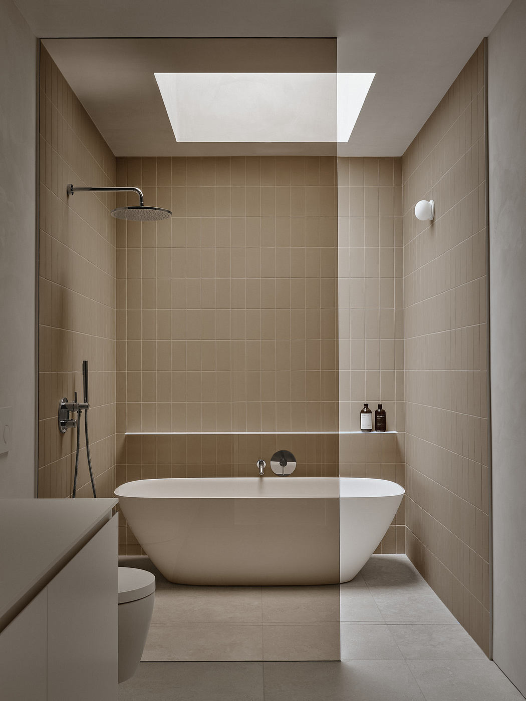 Minimalist bathroom design featuring a freestanding tub, sleek shower, and warm-toned tiles.