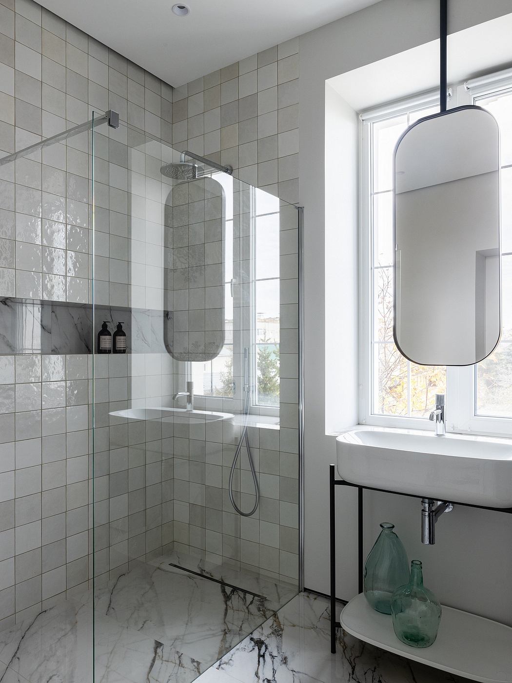 Modern, minimalist bathroom with floor-to-ceiling marble tiles, glass shower, and round mirror.