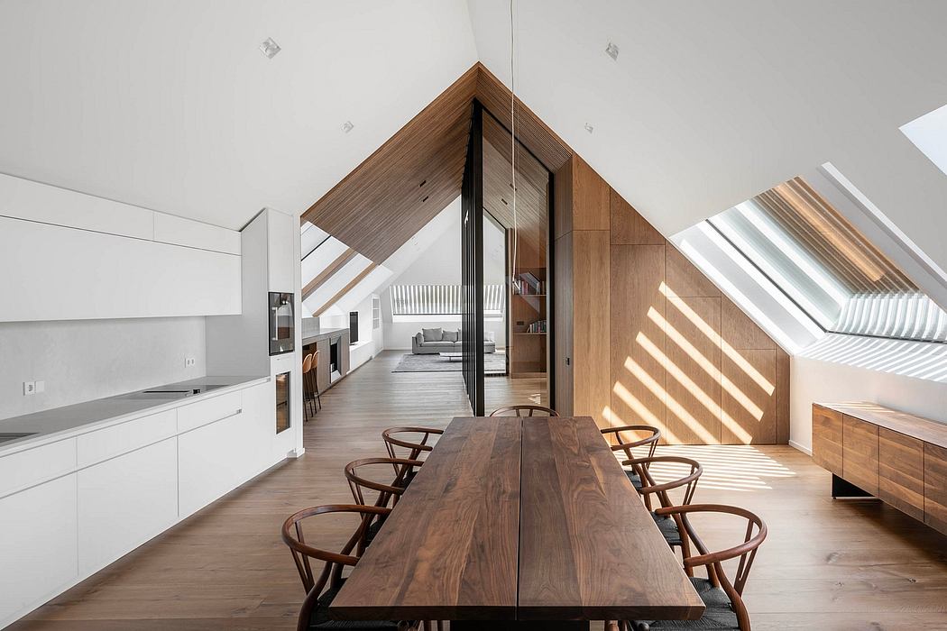 Bright, modern attic space with wooden slanted ceiling, dining table, and kitchen.