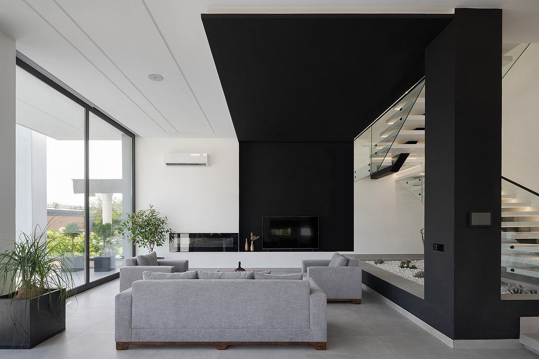 Spacious living room with modern black and white decor, large windows, and a sleek staircase.