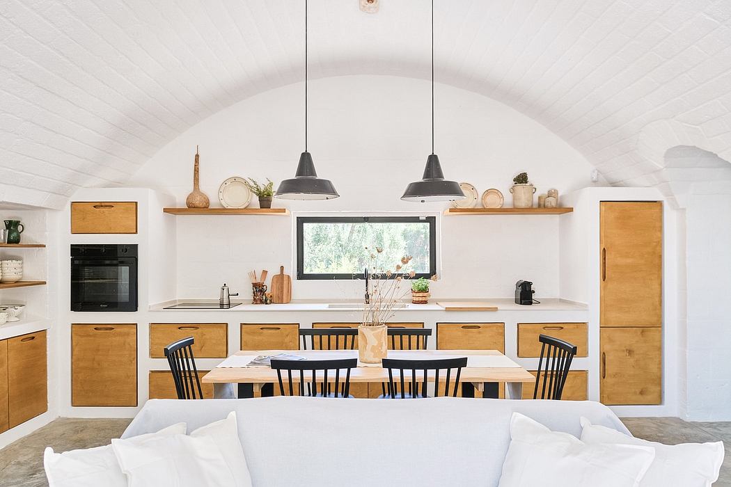 Cozy rustic kitchen with wooden cabinets, pendant lamps, and a dining table with black chairs.