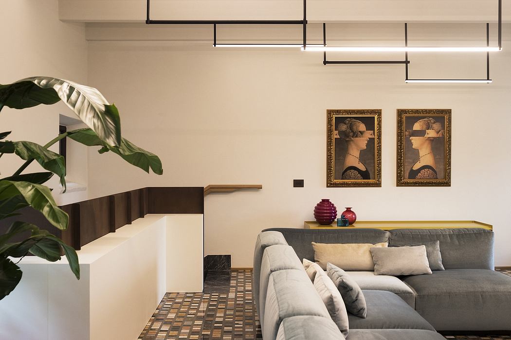 Minimalist living room with modern lighting, potted plant, and framed artwork on the walls.