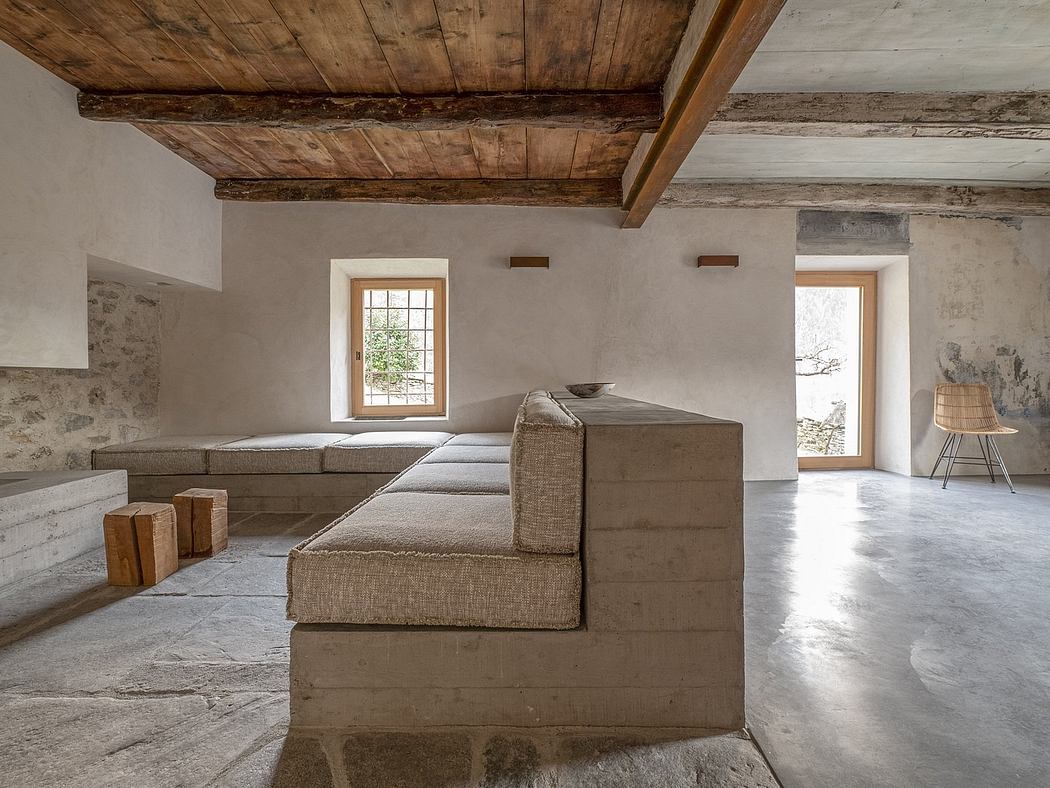 Rustic wooden beams contrast with minimalist concrete walls and furnishings in this cozy living space.