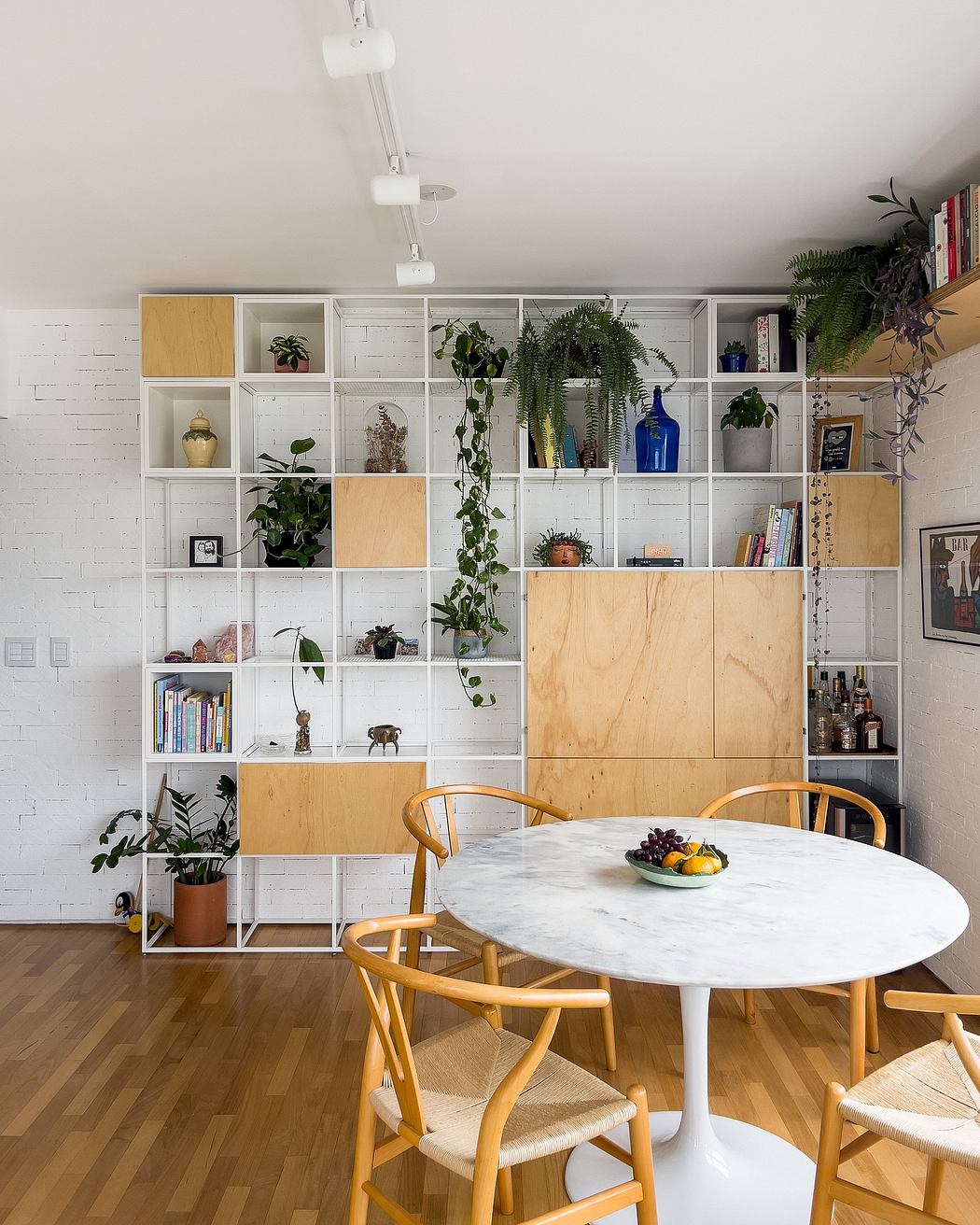 Minimalist living space with modular shelving, marble table, and natural wood furnishings.