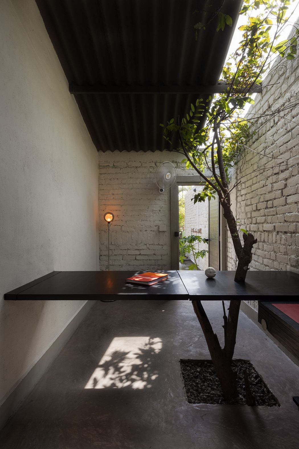 A modern, minimalist interior with a black table, brick walls, and a potted plant.