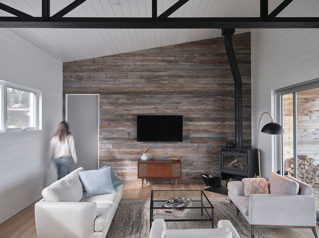 Cozy cabin living room with rustic wood paneling, fireplace, and modern furnishings.