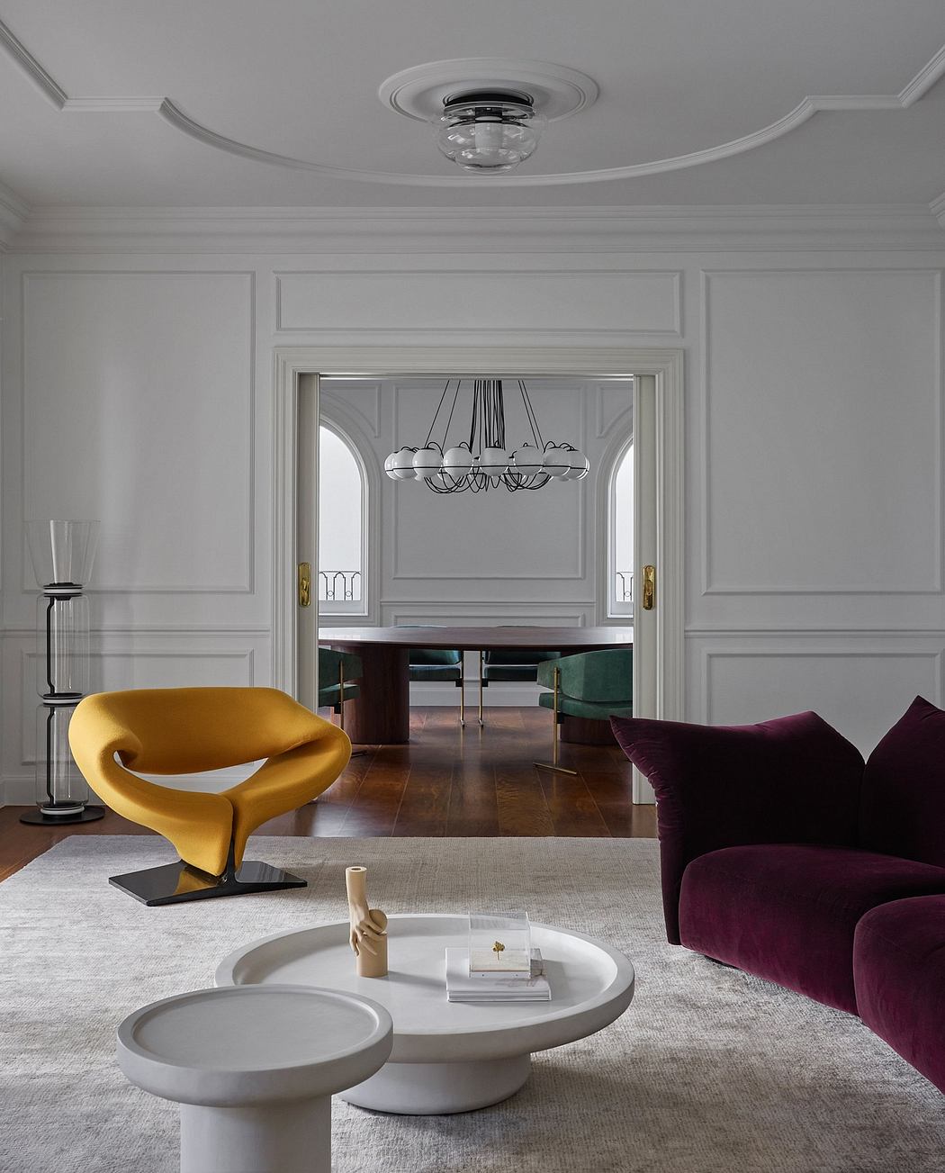 Elegant gray living room with plush velvet sofa, sculptural yellow chair, and ornate chandelier.