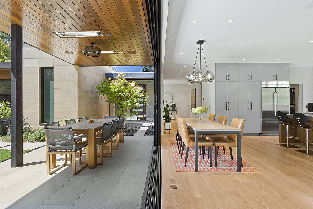 A modern open-plan kitchen and dining area with sleek wood and stone finishes.