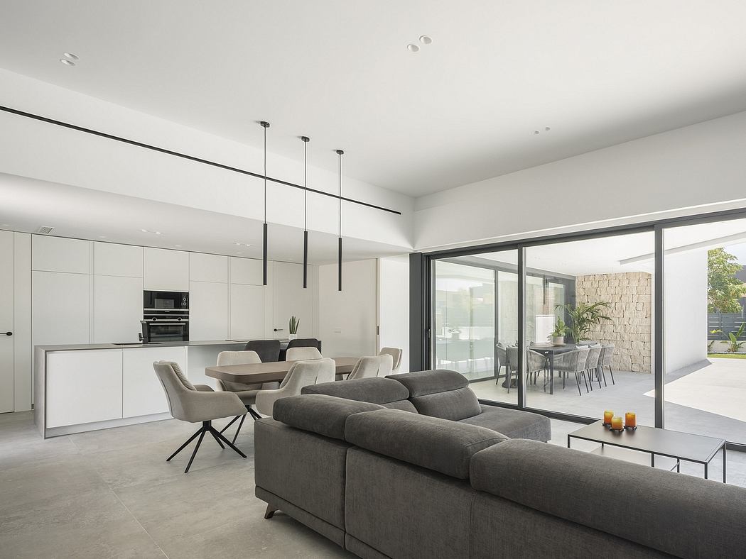 Sleek, modern interior with gray sofas, minimalist kitchen, and large sliding glass doors.