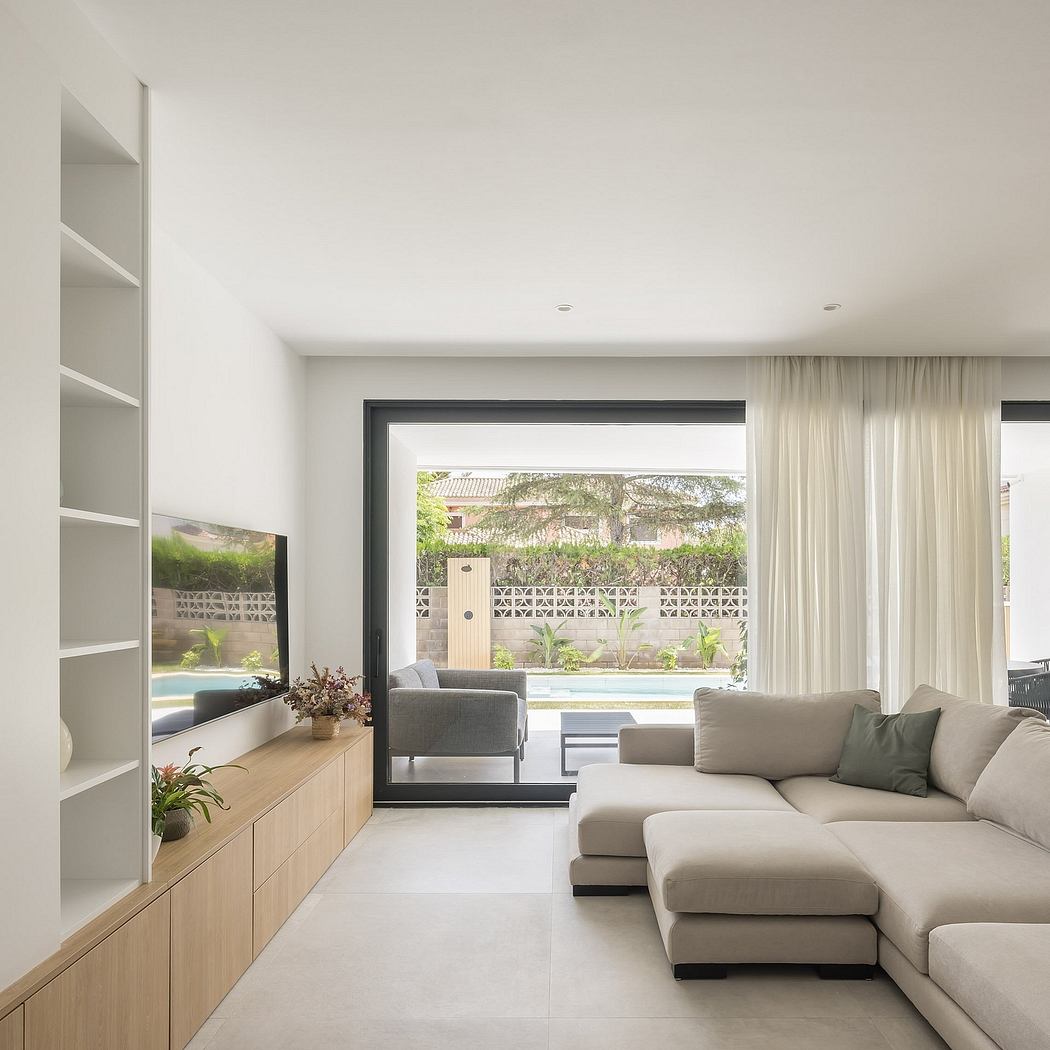 Spacious living room with sleek furniture, floor-to-ceiling glass doors, and lush outdoor view.