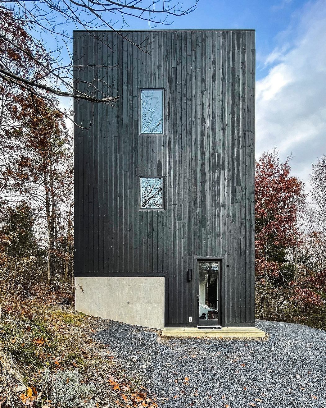 A modern, minimalist cabin-like structure with vertical wooden siding and square windows.
