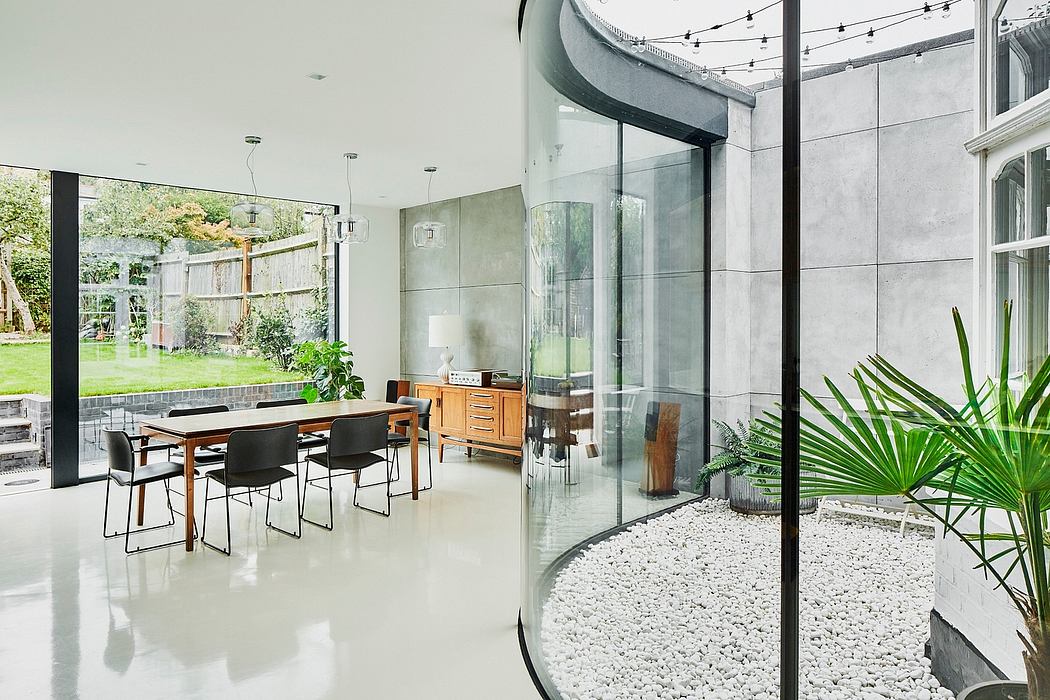 Sleek, modern dining area with glass walls overlooking lush garden, showcasing sophisticated interior design.