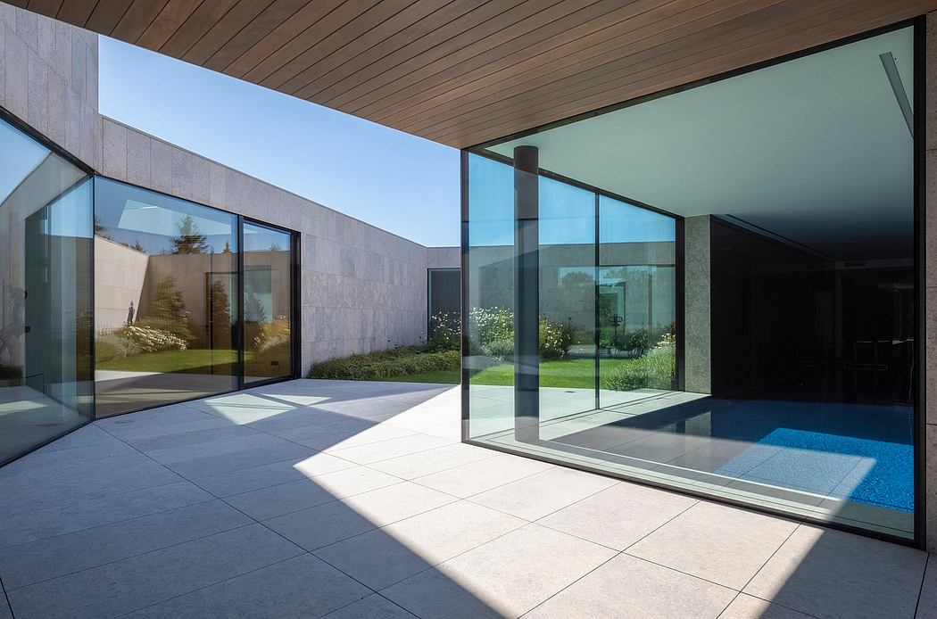 Modern glass and concrete architecture with a pool and landscaped garden.