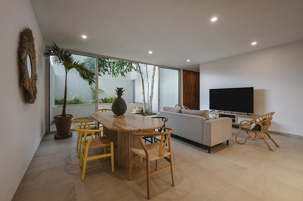 Spacious, modern living area with large windows, wooden furniture, and tropical decor.