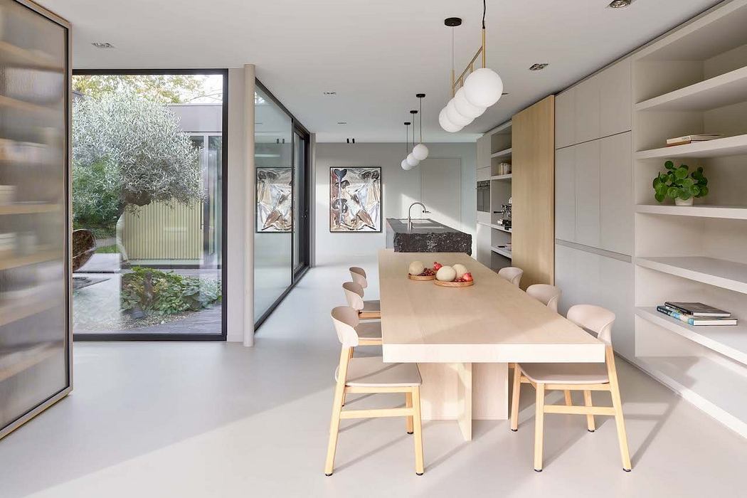 A modern, minimalist dining area with full-length windows overlooking greenery.