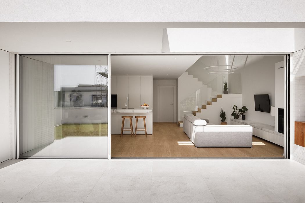 Minimalist open-concept living space with glass walls, modern furnishings, and clean lines.