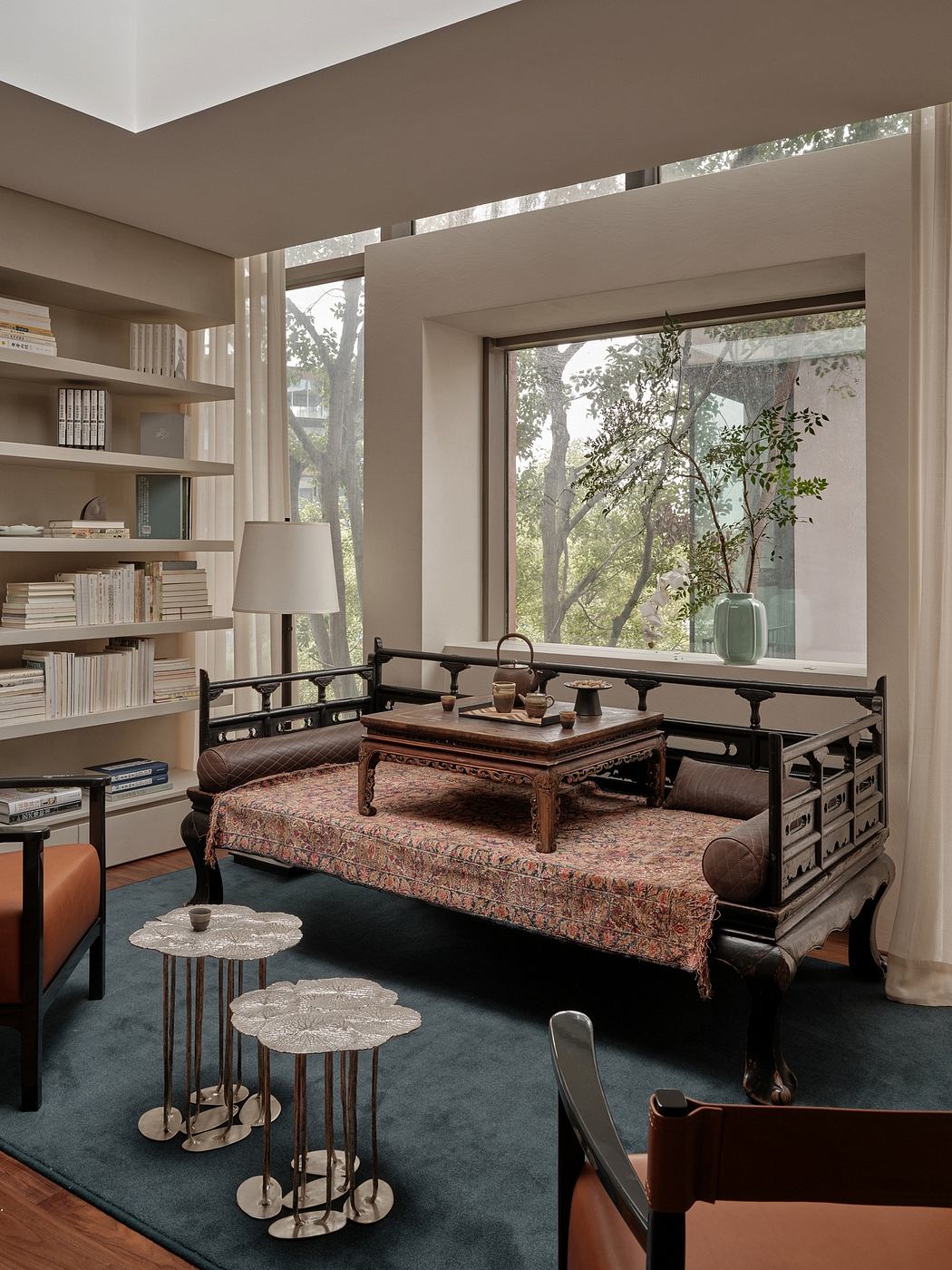Cozy living room with plush seating, ornate coffee table, and floor-to-ceiling windows showcasing nature.