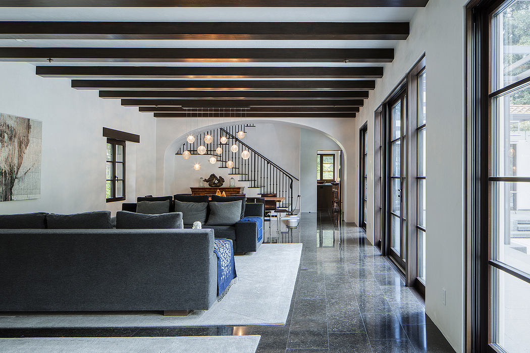 Spacious open-concept living area with exposed wooden beams, modern lighting, and sleek tile flooring.