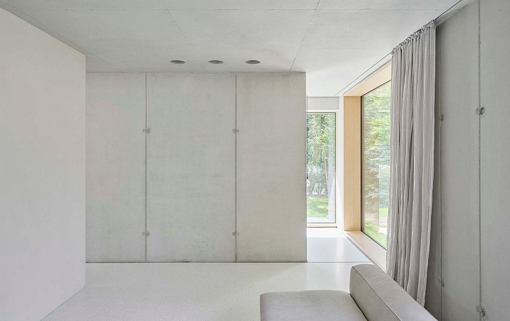 A minimalist, clean-lined interior with large windows, concrete walls, and gray curtains.