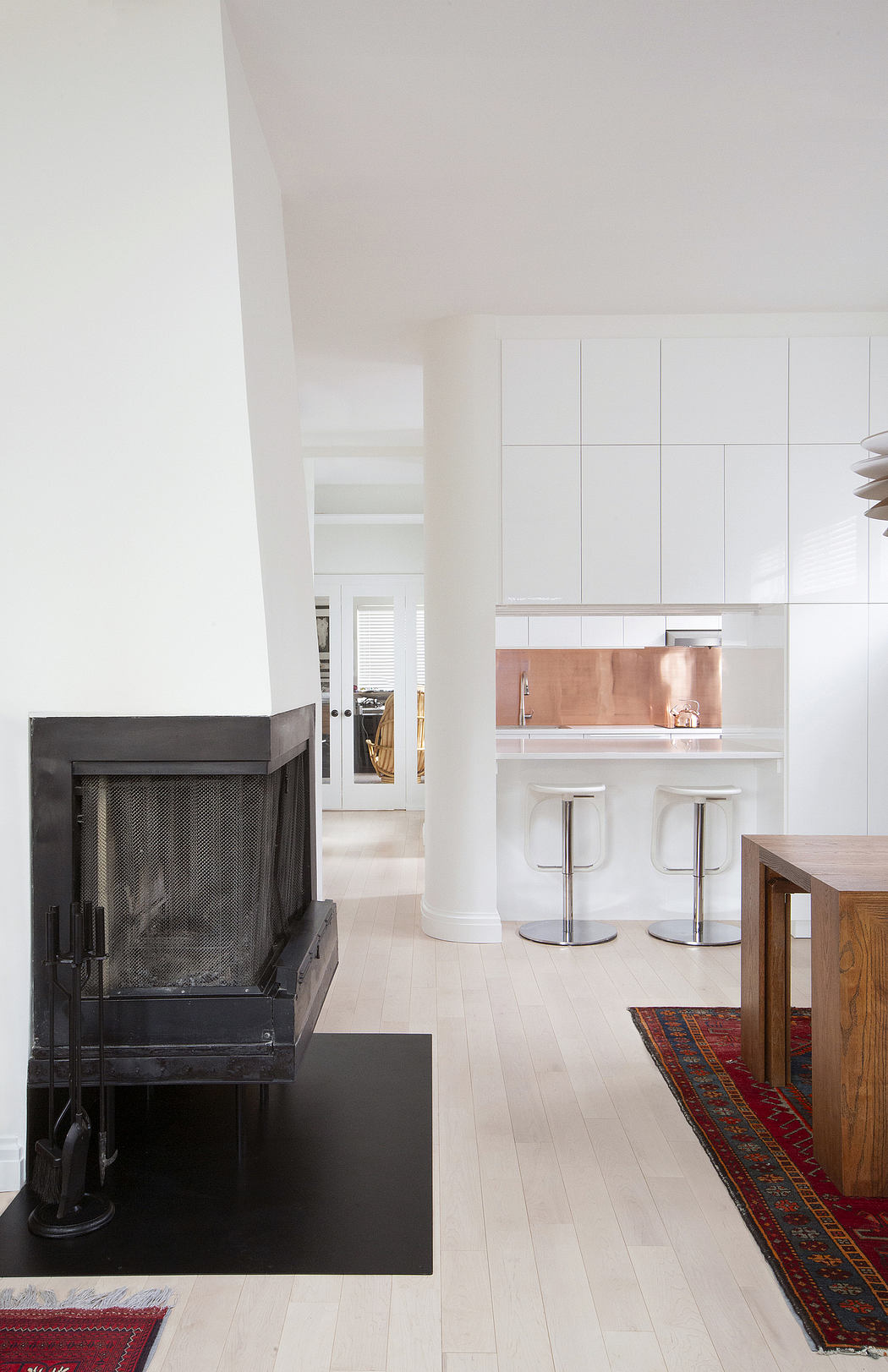 A modern, minimalist kitchen with a copper backsplash and a sleek, black fireplace.