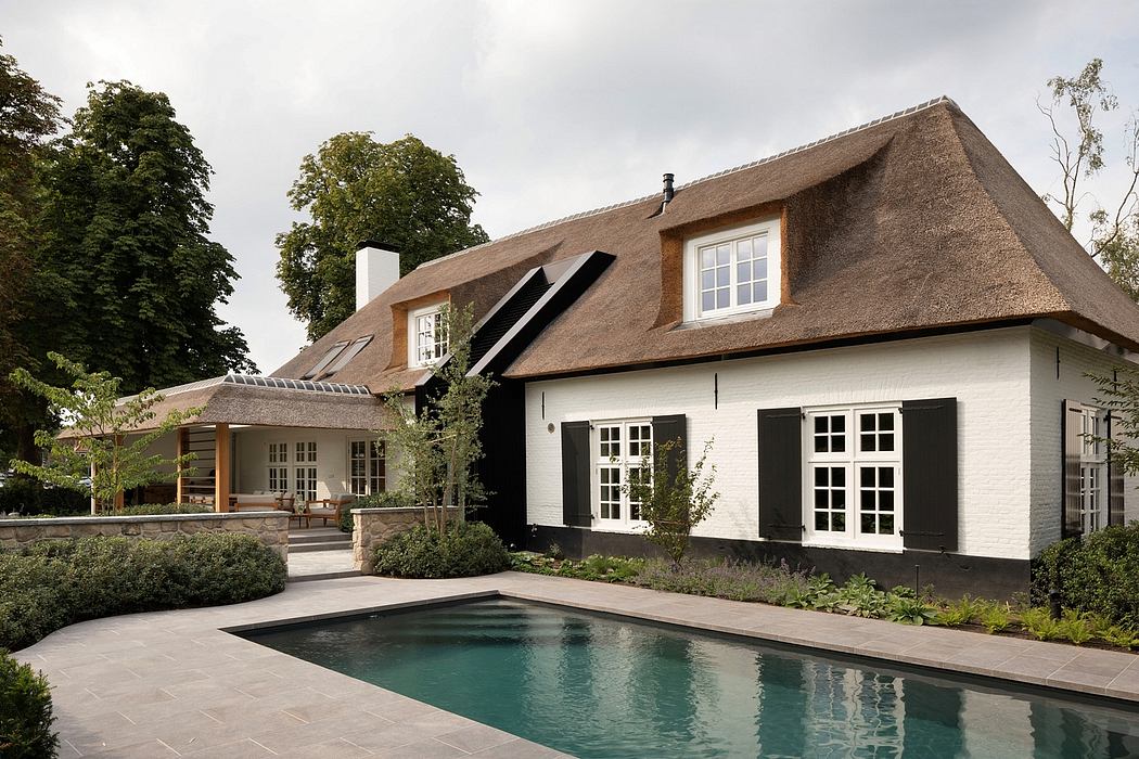 Charming thatched-roof home with a patio, pool, and traditional design elements.