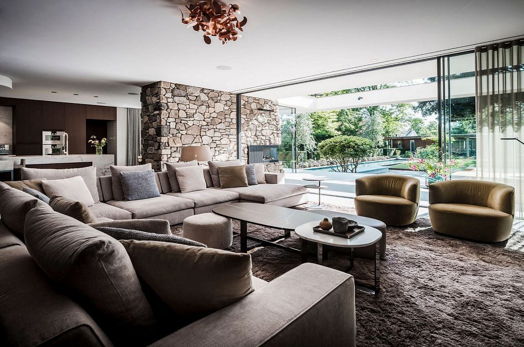 Lavish living room with stone accent wall, plush seating, and expansive glass windows overlooking lush greenery.