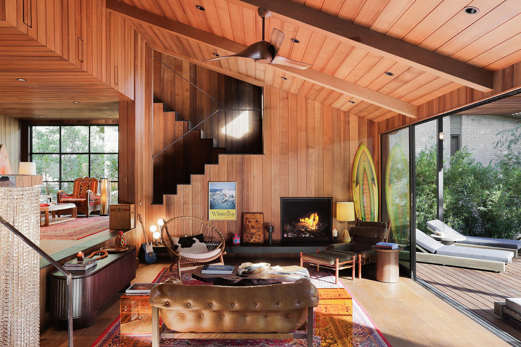 Warm, cozy wooden interior with a fireplace, mid-century furnishings, and a deck view.