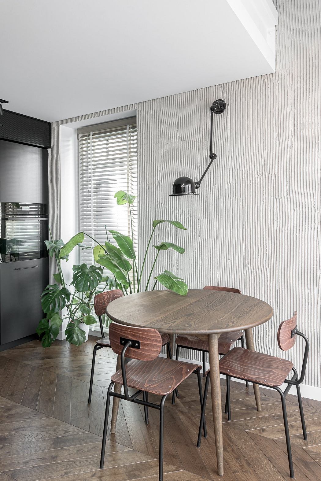 Cozy dining nook with a round wooden table, metal chairs, and lush tropical plants.