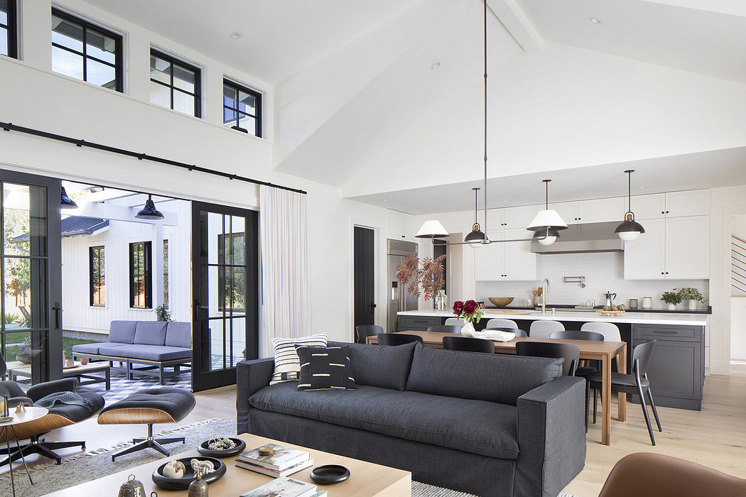 High-ceilinged open-concept living space with modern furniture, lighting, and kitchen.