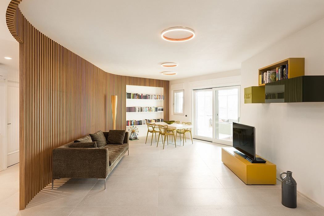 Open-concept living room with wood-slatted accent wall, built-in shelving, and sleek furnishings.