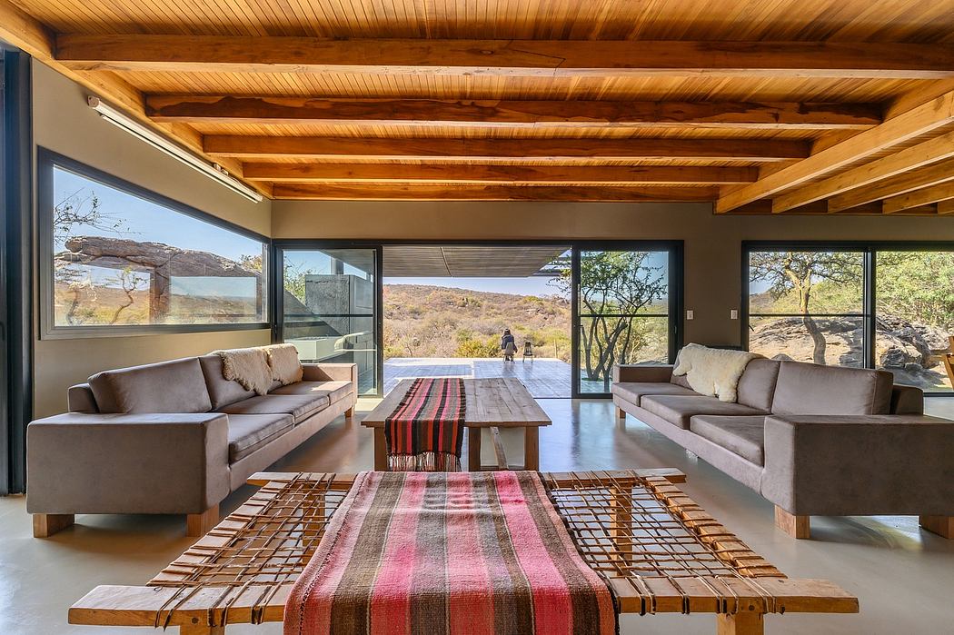 Rustic modern interior with wooden beams, large windows, and colorful textile accents.