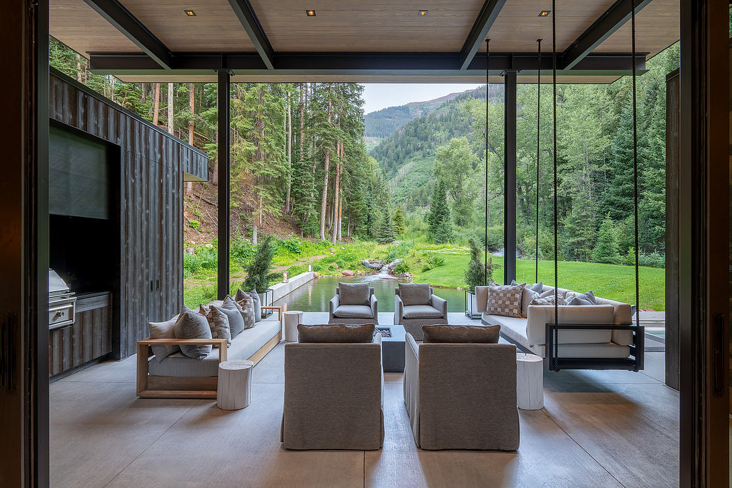 A spacious and modern mountain-side living room with large glass walls and lush forest views.