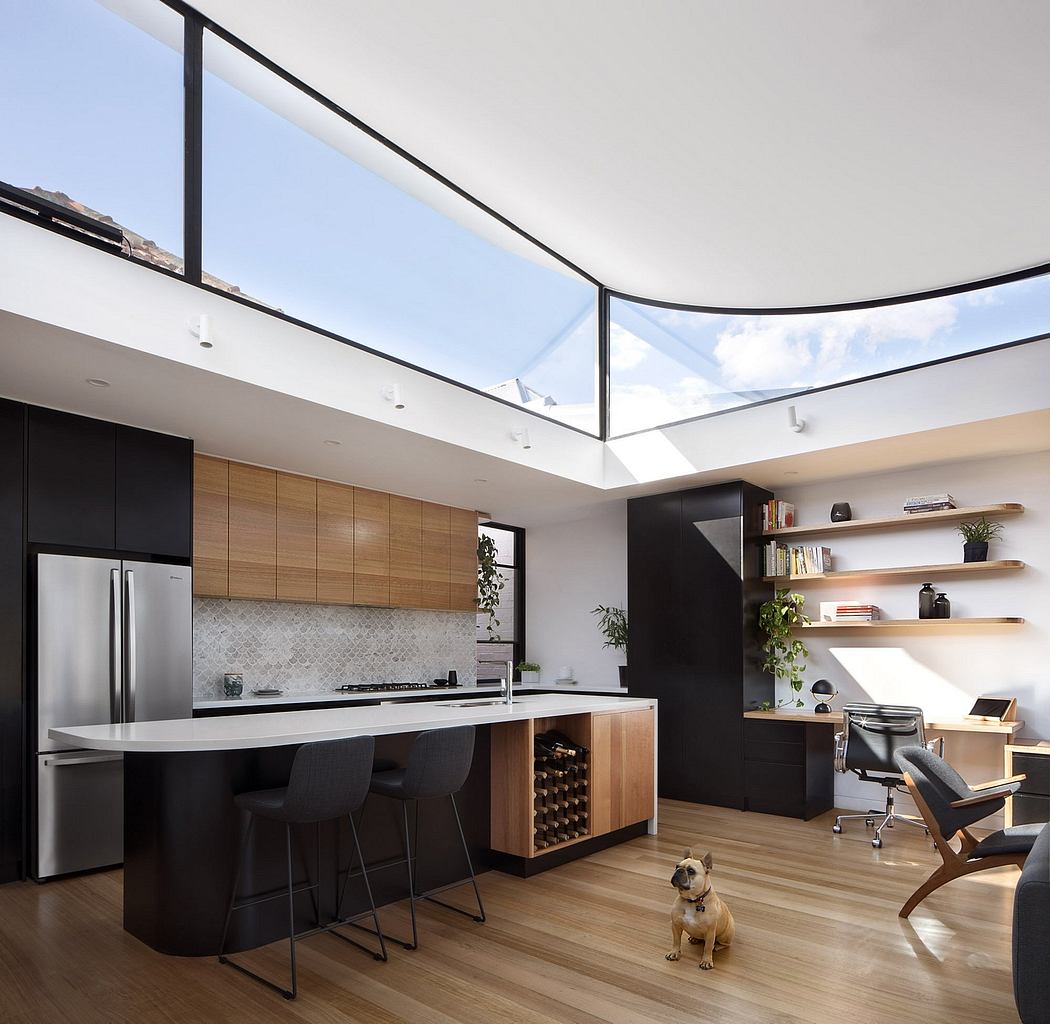 Sleek, modern kitchen with wooden cabinets, large skylight, and open-concept living space.