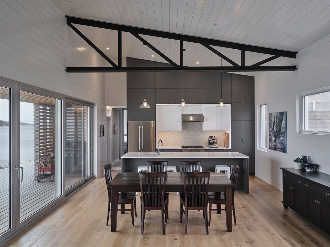 Modern kitchen with dark cabinetry, exposed wood beams, and a dining table with chairs.