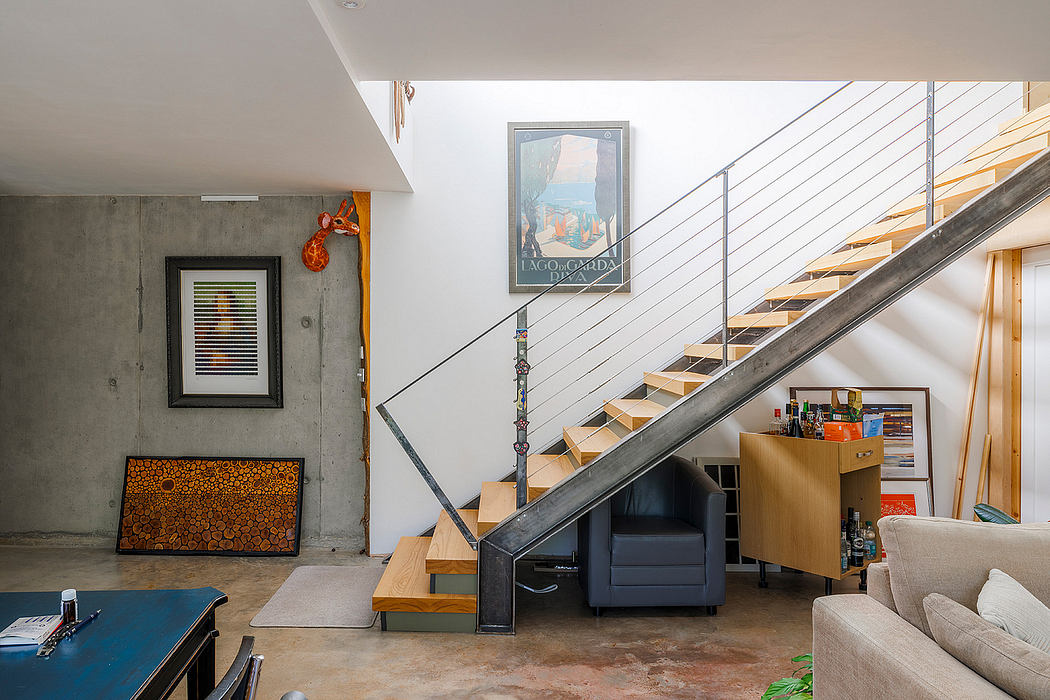 A modern, open-concept interior with a concrete staircase, artwork, and furniture.