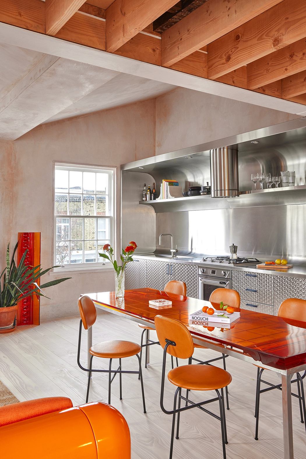 Rustic wood ceiling beams contrast with sleek stainless steel kitchen appliances.