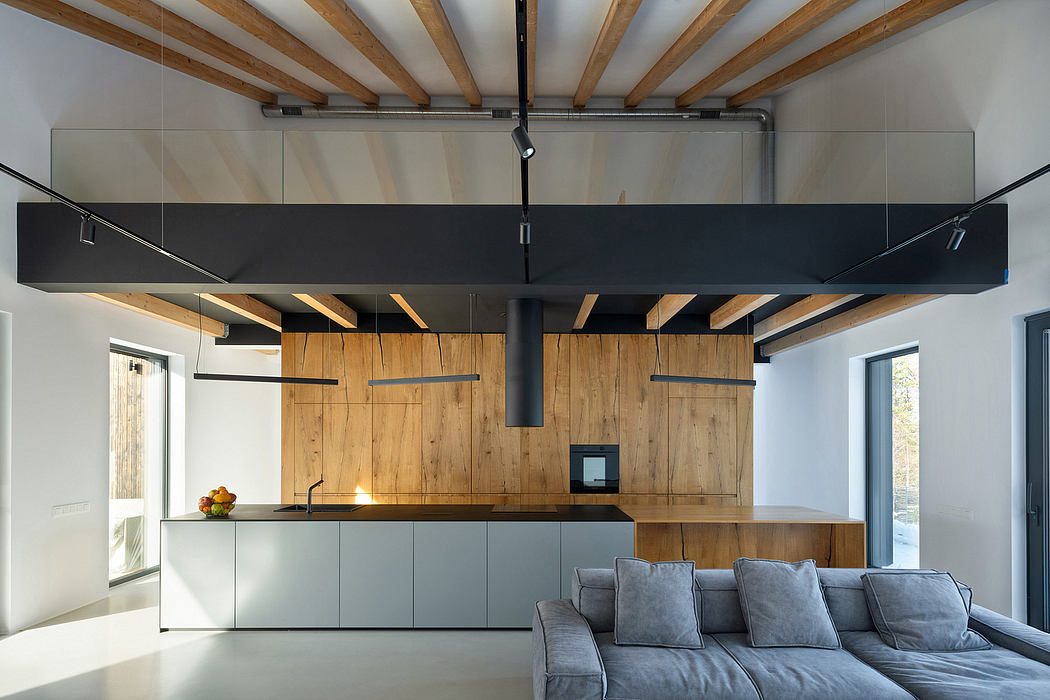 A modern kitchen with wood-paneled walls, a sleek black range hood, and a cozy gray sofa.