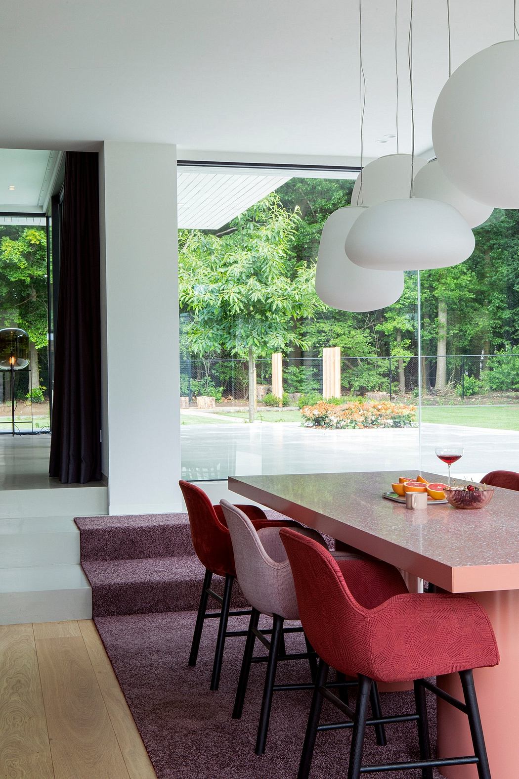 Sleek modern interior with clean lines, large windows, and plush red accent chairs.