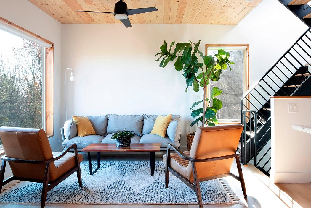 Cozy living room with wood-paneled ceiling, blue sofa, orange armchair, and potted plant.