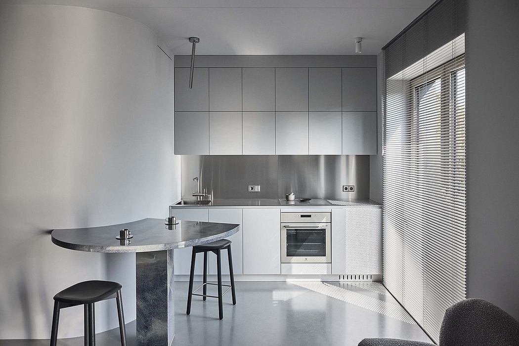 Minimalist kitchen with sleek gray cabinetry, stainless steel appliances, and a curved breakfast bar.