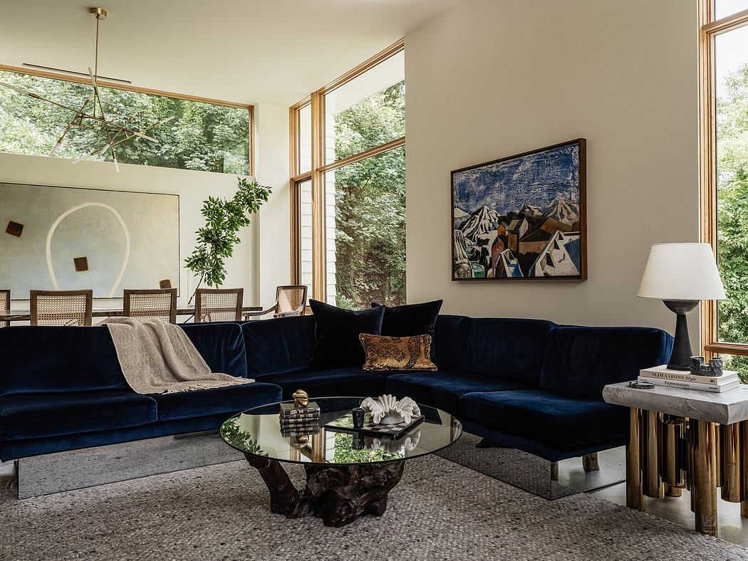Elegant modern living space with plush navy sofa, nature-inspired art, and expansive windows.