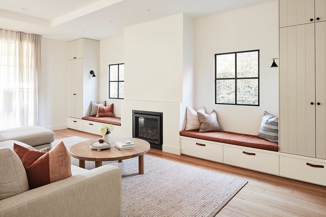 A spacious, light-filled living room with built-in window seats, wooden accents, and a fireplace.